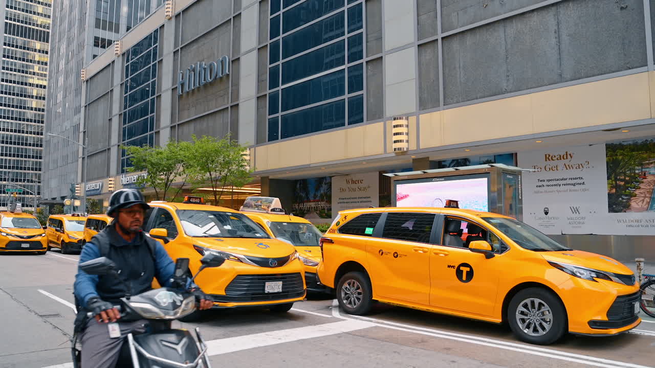 New York, AS, 28 Agustus 2025: POV: Menyeberang jalan di kota metropolitan. Banyak mobil kuning berhenti di lampu lalu lintas merah. Lalu lintas siang hari New York, AS