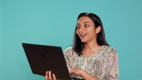 Upbeat-woman-saluting-coworkers-during-teleconference-meeting-using-laptop