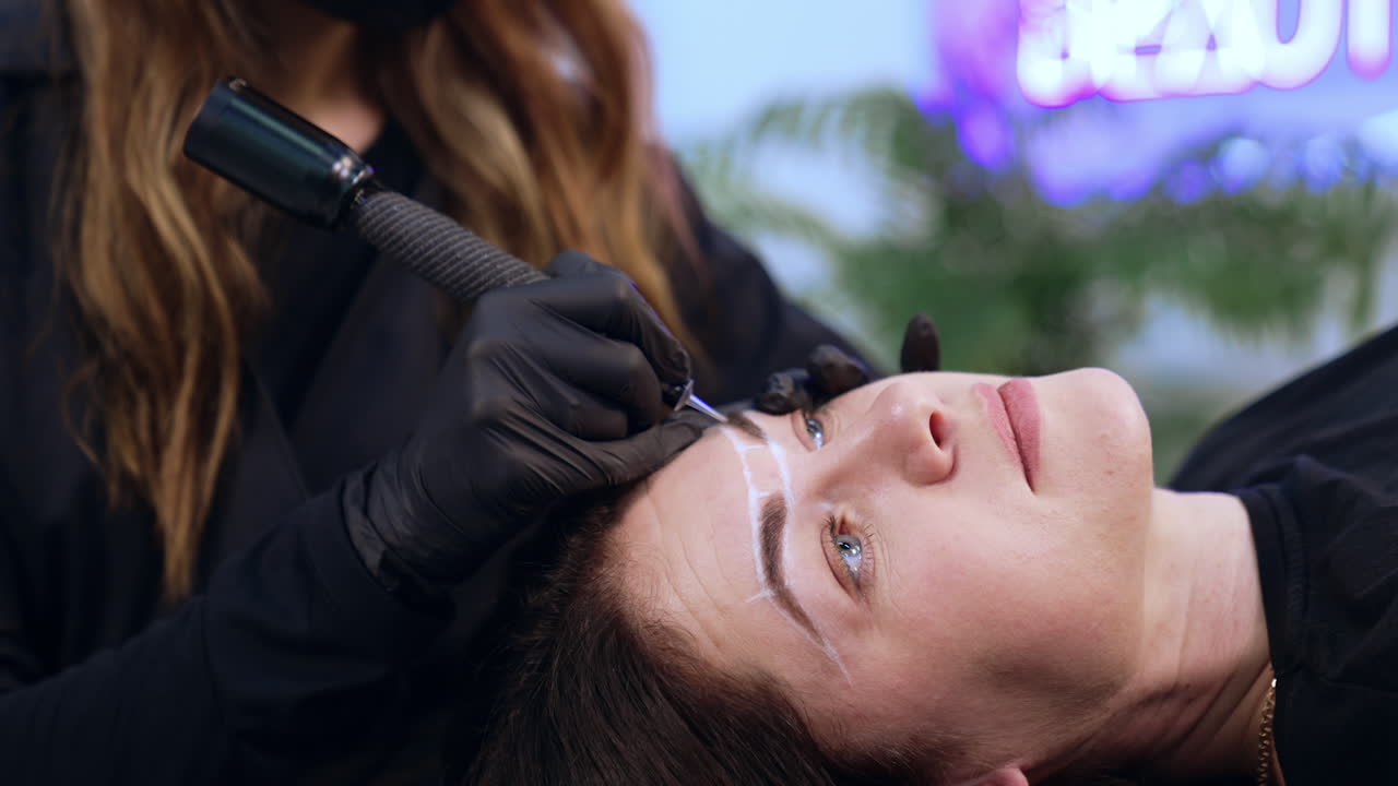 Beautiful adult lady is a client of brow master. Client having the permanent make up procedure for eyebrows. Close up.