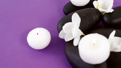 Close-up-of-pebble-stones-with-flowers-and-candles