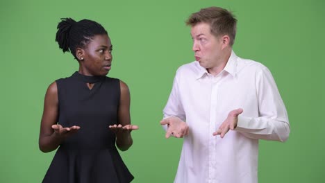 two young multi-ethnic business couple shrugging shoulders together