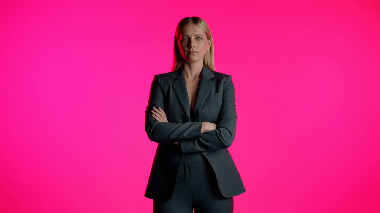 Confident Caucasian Woman In Suit Poses With Arms Crossed Against Vibrant Pink Studio Background, Serious