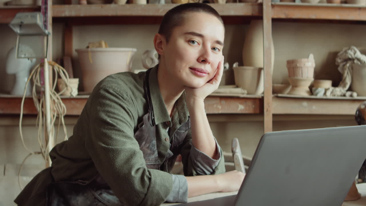 Portret van pottenbakster met laptop in atelier