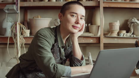 portrait of female potter with laptop in workshop