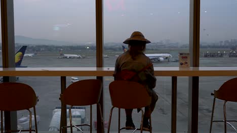 person dining alone in mumbai airport looking at airplanes - medium shot