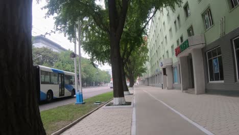 first person pov walking along footpath of sungri street, downtown pyongyang, north korea