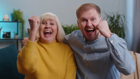 Senior-grandmother-with-grown-up-son-or-grandson-shouting,-celebrating-success,-winning,-good-news