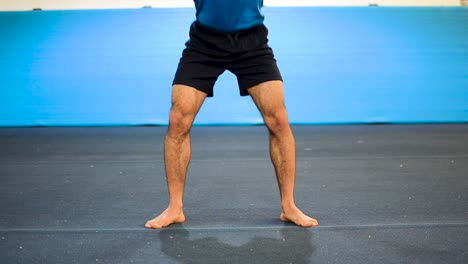 a still shot of a guy doing squats in a gymnastics gym