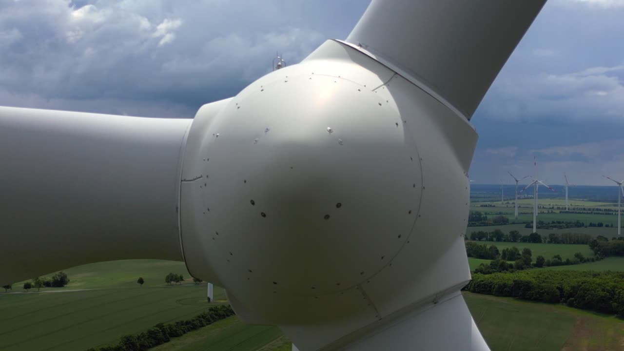 Wind turbines generating clean energy in a large wind park in Germany, under a cloudy sky. close up Best aerial view flight static tripod hovering drone