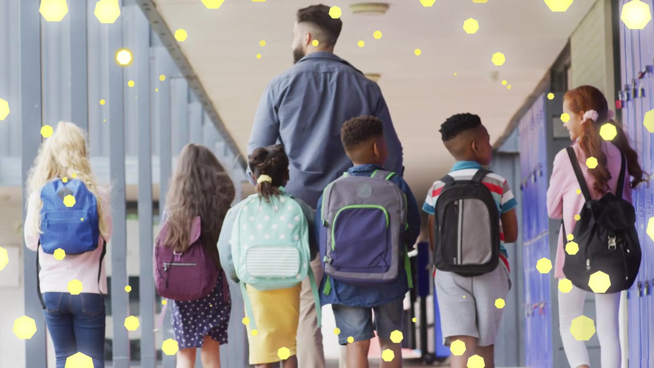 Adult male leading students walking school corridor, yellow bokeh overlay growing over blue lockers