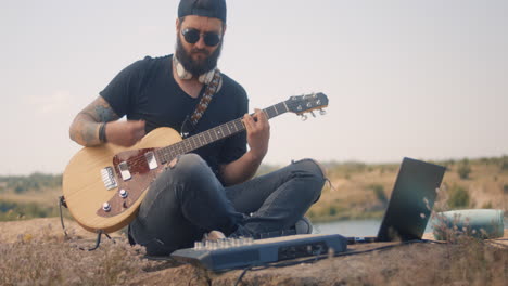man playing guitar and recording music outdoors