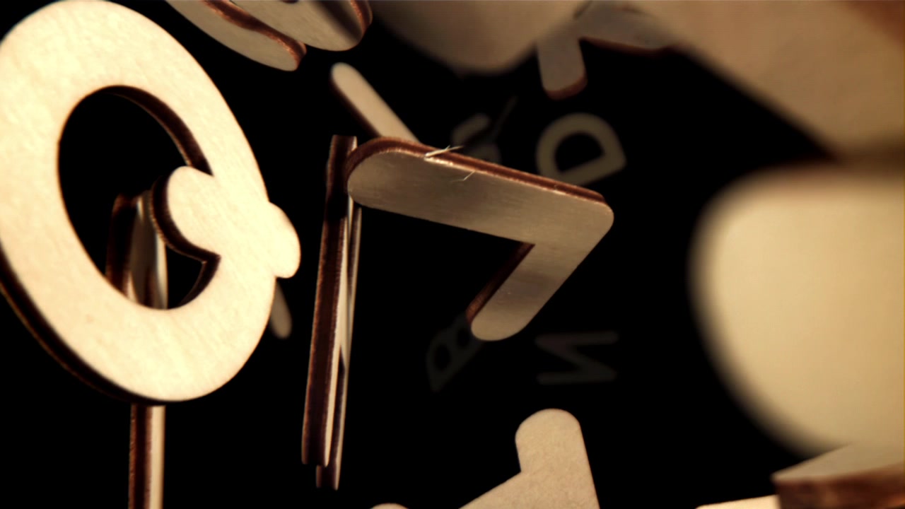 Close-up of Wooden Letters Falling on a Reflective Black Surface