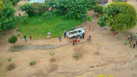 drone flying over a village with a car driving towards it