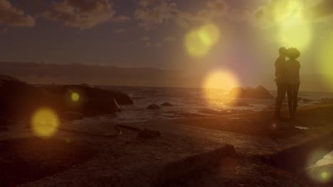 manchas amarillas brillantes de luz cayendo contra una pareja afroamericana de pie juntos en las rocas