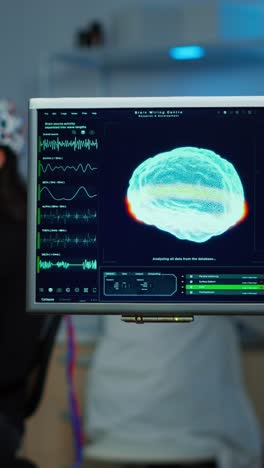 woman undergoing brain activity monitoring with eeg cap and computer display