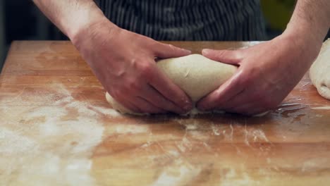 closeup, baker's hands knead bread dough and spread out into shape