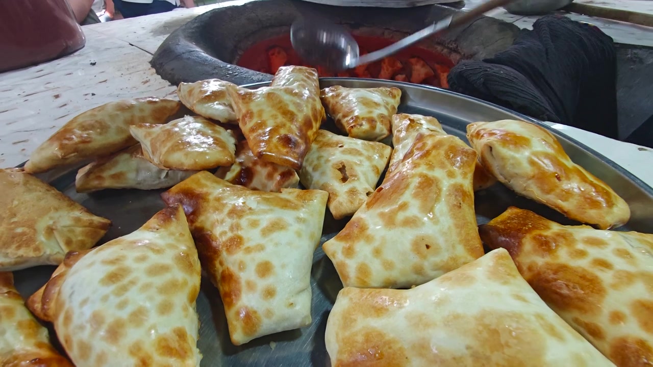 Chef che estrae Samsa appena sfornato da un tradizionale forno tandoor