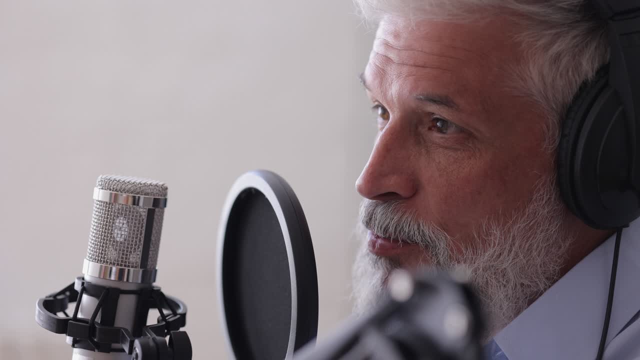 uomo registra un podcast o un'intervista con un microfono in uno studio di registrazione. ingegnere del suono senior o conduttore radiofonico. un uomo adulto dai capelli grigi crea contenuti audio