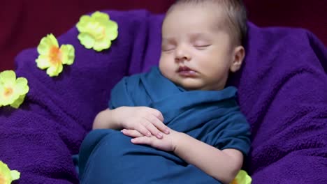 lindo bebé recién nacido durmiendo en una envoltura de bebé con flores en un estilo único desde el ángulo superior
