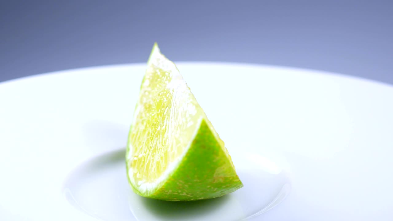 una rebanada de limón verde está girando lentamente en el estudio con los detalles.