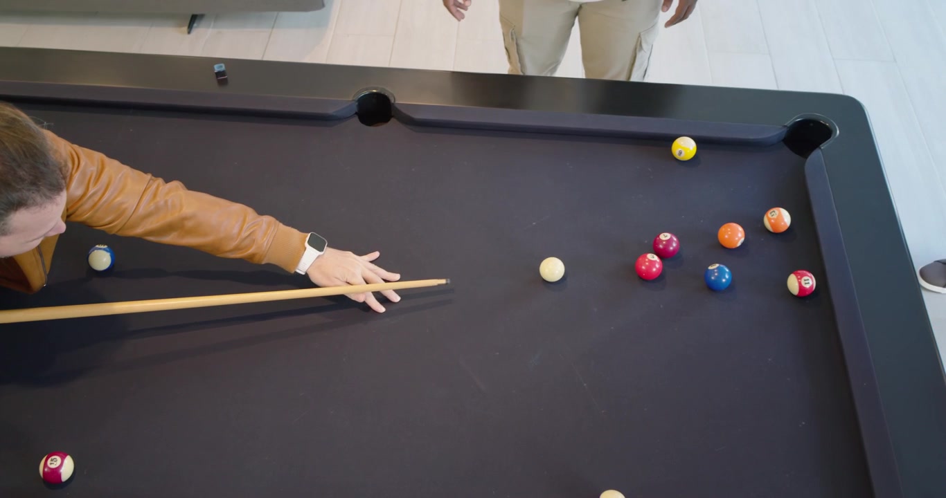 Diverse males playing pool, man in jacket lining, striking cue ball breaking rack, copy space