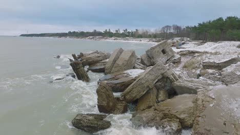 aerial view of abandoned seaside fortification buildings at karosta northern forts on the beach of baltic sea , overcast winter day, wide drone shot moving forward