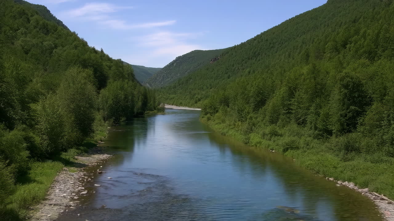 Joki virtaa rehevän vihreän laakson läpi metsäisten vuorten ympäröimänä