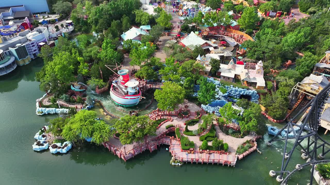 Universal Studios in Orlando with many visitors on sunny day. Amusement Park with rollercoaster, boats and river water park in theme park. Wide shot. Florida, USA. Aerial top down.