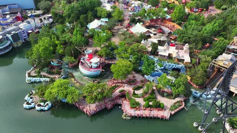 universal studios in orlando with many visitors on sunny day. amusement park with rollercoaster, boats and river water park in theme park. wide shot. florida, usa. aerial top down.