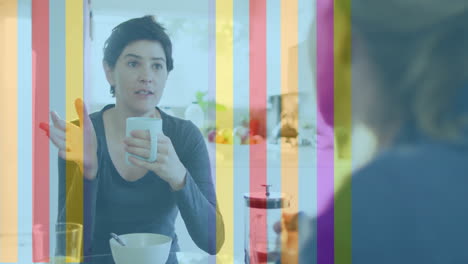 animation of pride rainbow stripes over caucasian lesbian couple talking at breakfast