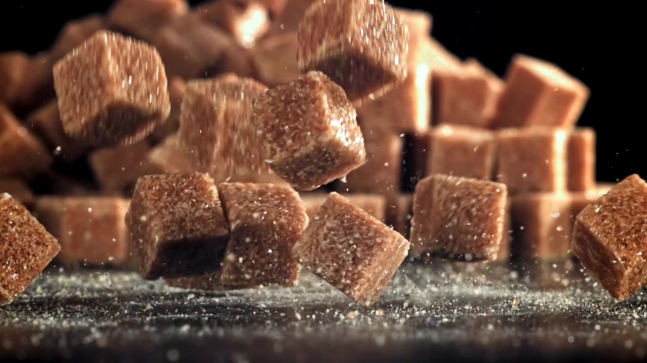 Slow Motion of Brown Sugar Cubes Dropping onto a Black Surface