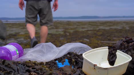 hombre camina sobre basura plástica en la playa