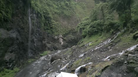 Low-aerial-flies-up-hazy-steep-narrow-jungle-canyon-on-Java,-Indonesia