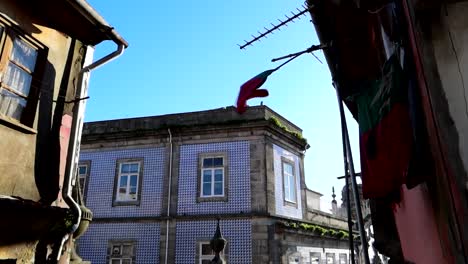 portuguese flag waving and typical blue and white tiled facade in background, porto