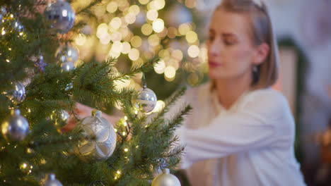 woman decorates beautiful live christmas tree during christmas