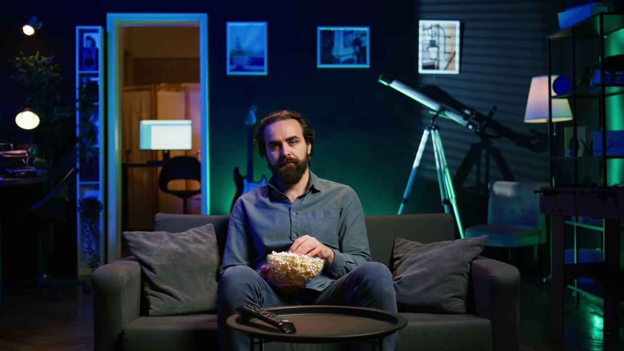 hombre triste sentado en el sofá sintiendo el corazón roto mientras ve una película trágica