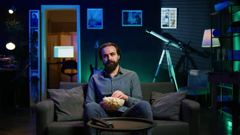 sad man sitting on couch feeling heartbroken while watching tragic movie