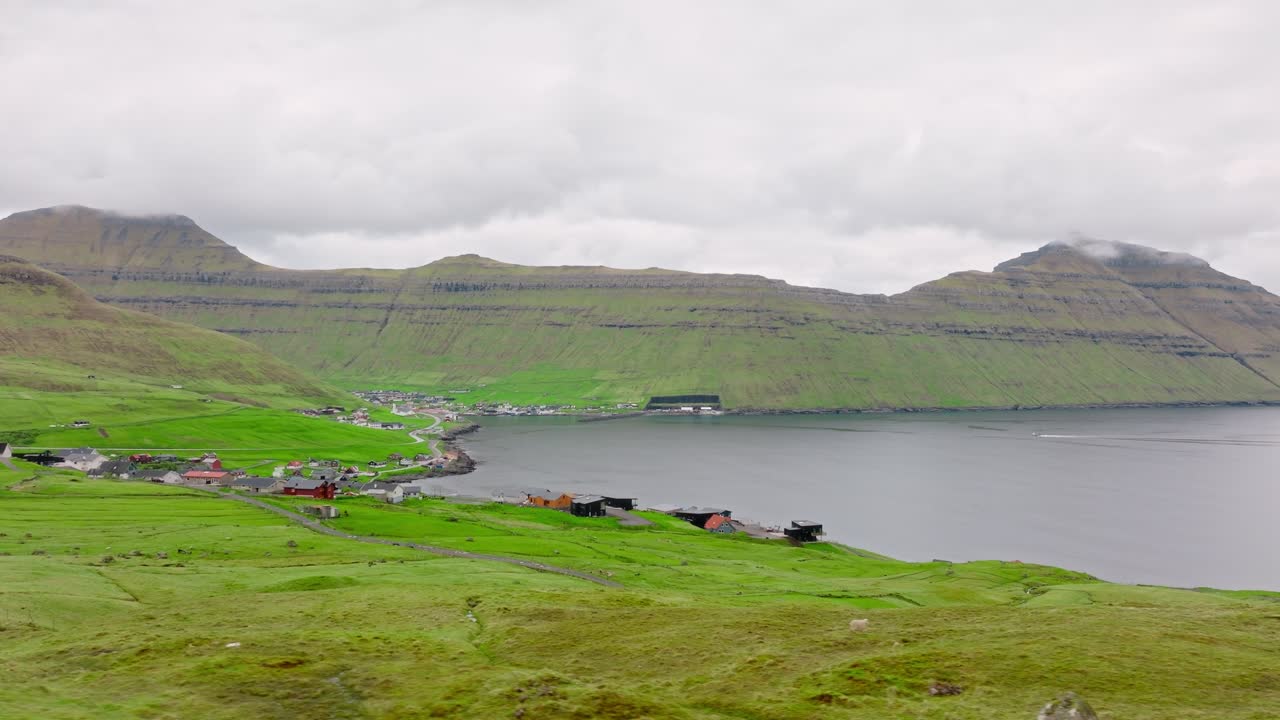 A remote coastal village in the Faroe Islands with lush green hills and mountains