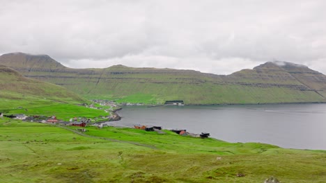 a remote coastal village in the faroe islands with lush green hills and mountains