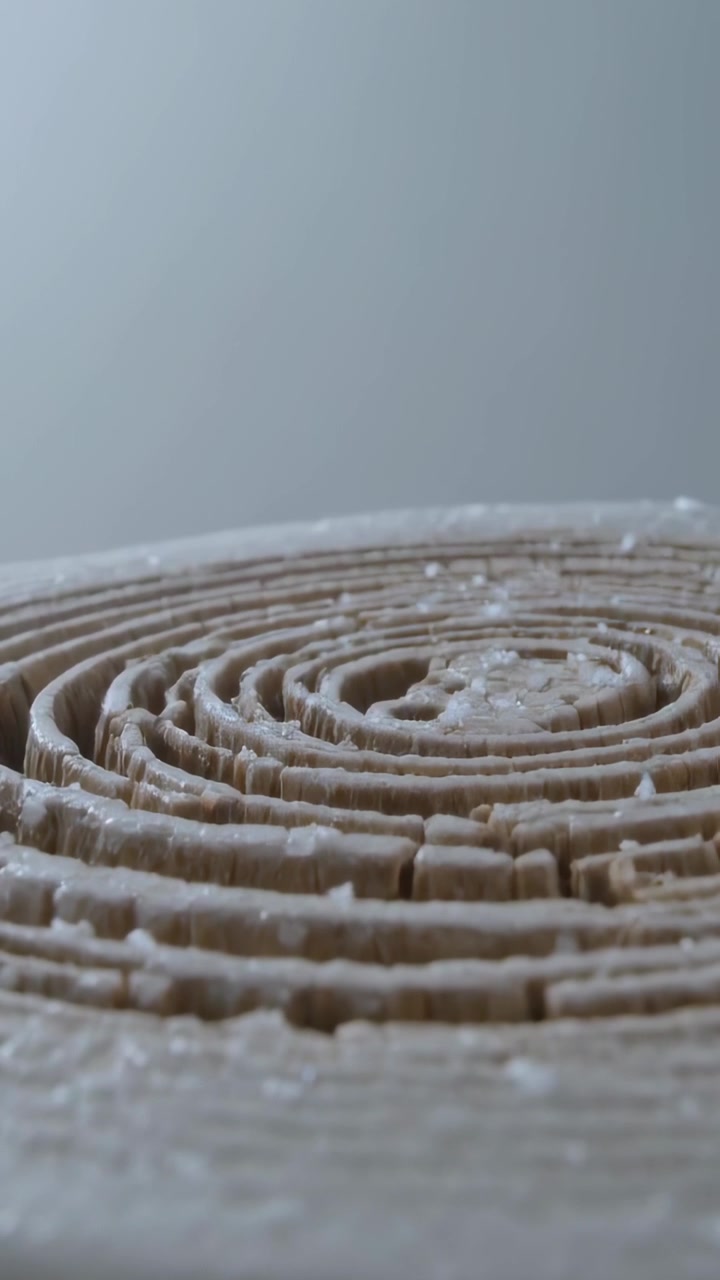 Vertical video: Lifting camera revealing coiled roll on block at studio to expose pale residue