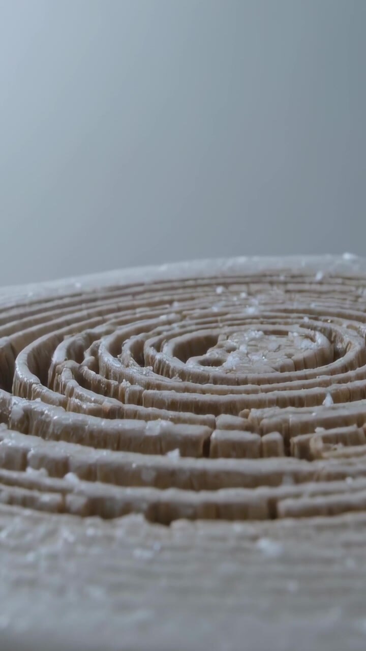 Vertical video: Lifting camera revealing coiled roll on block at studio to expose pale residue