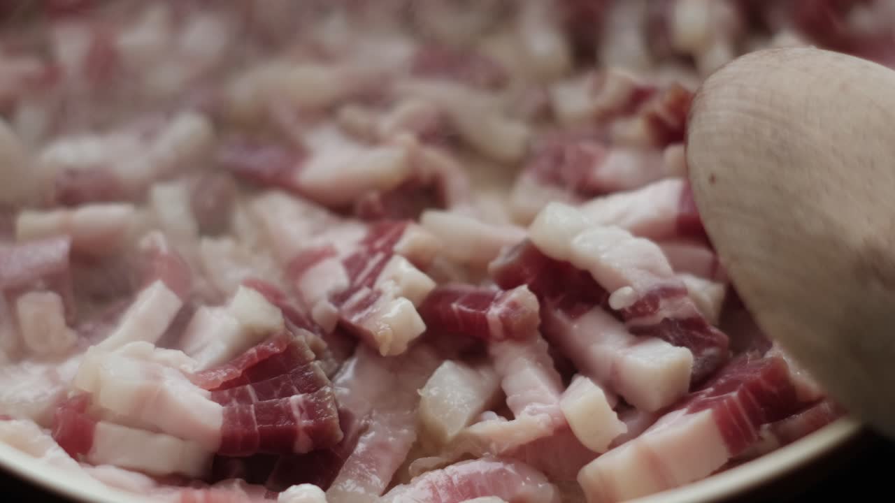 Sizzling Goodness: Slow Motion Close-Up of Pancetta and Guanciale Strips Cooking for Carbonara. Italian Cuisine