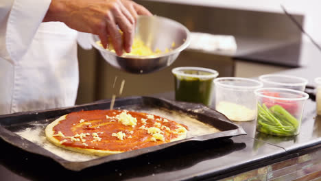 Chef-Espolvoreando-Queso-Sobre-Una-Pizza