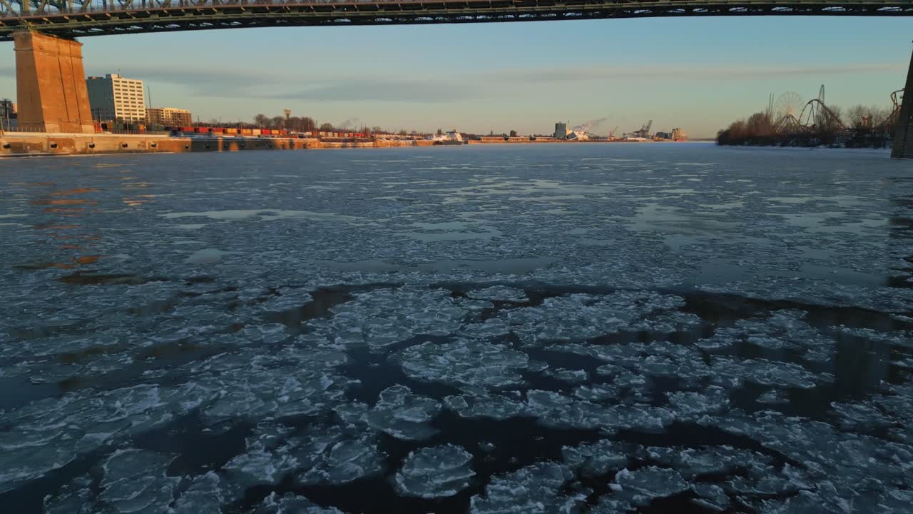 An icy river surface with drifting ice chunks under Jacques Cartier bridge in winter, North America, Quebec, Montreal, Canada.