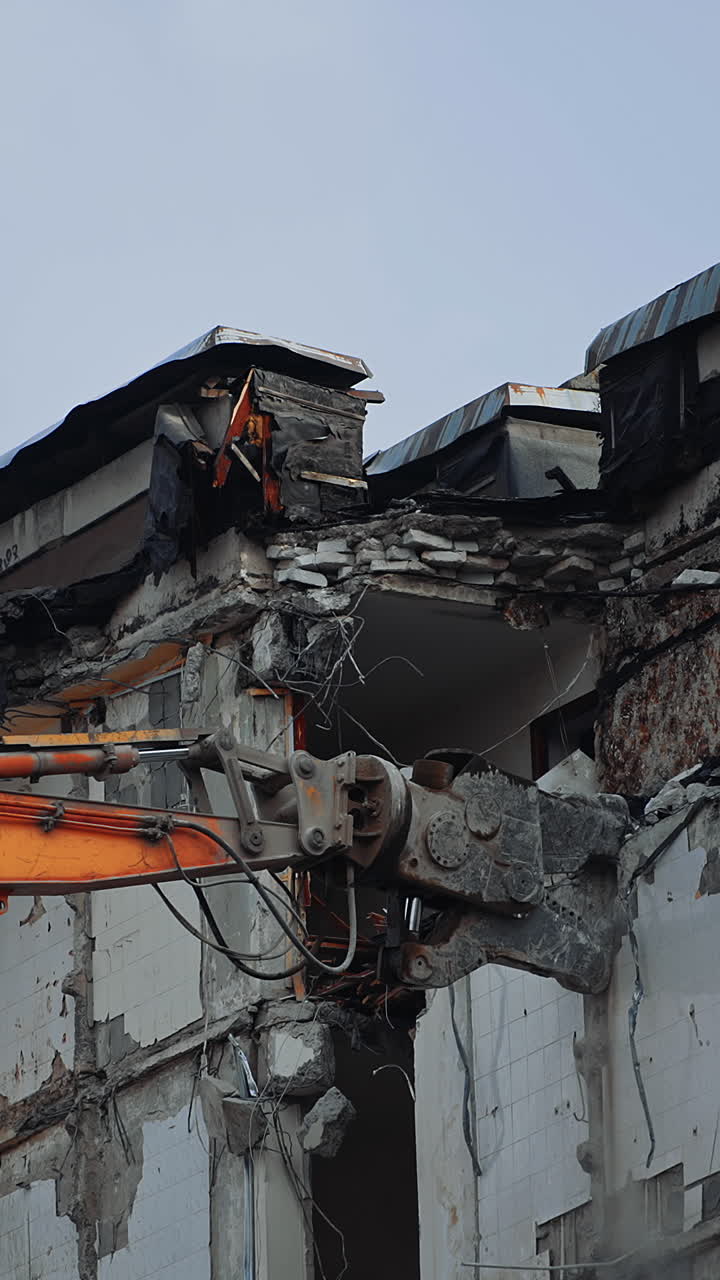 Breaking off the walls of the building with the help of demolishing machinery. Dismantling the building ruined by the natural disaster. Vertical video