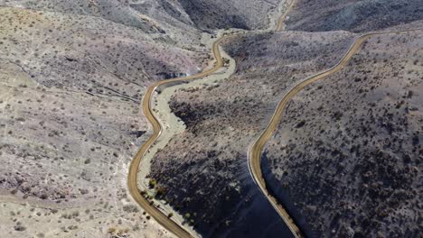 Unpaved-road-descends-from-rustic-hills-into-narrow-remote-valley