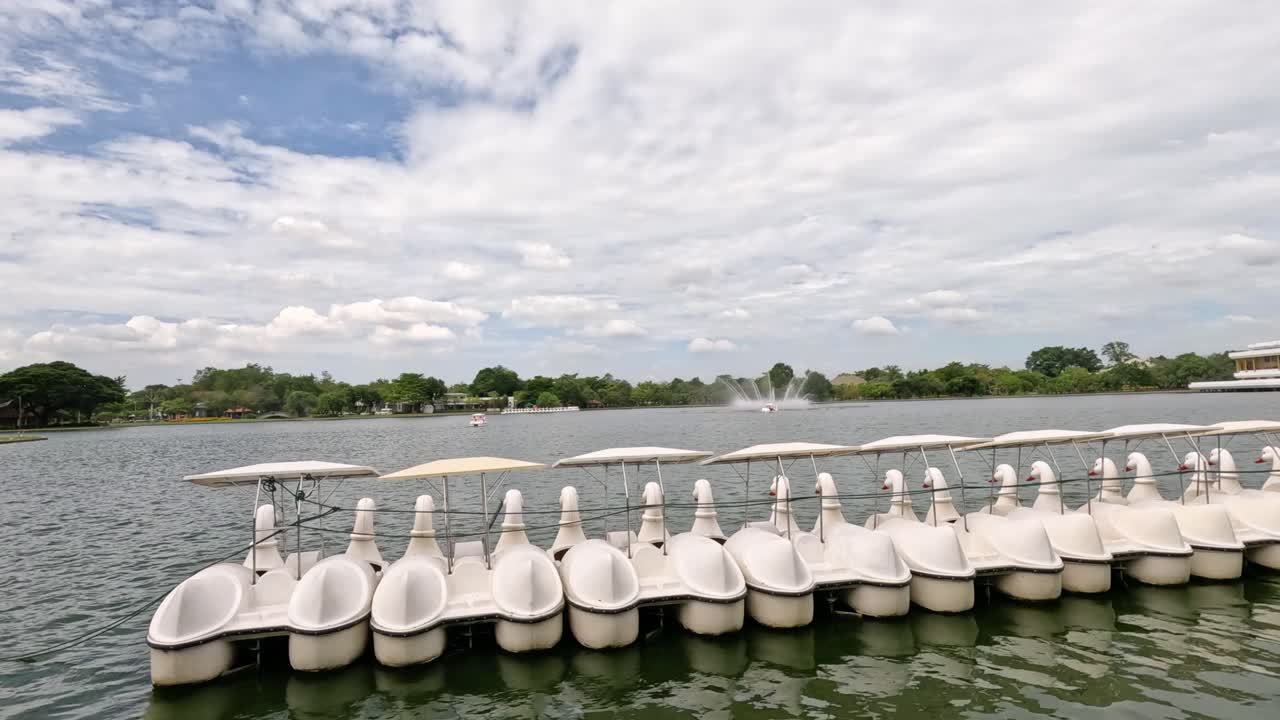 barcos de pedales flotando en un lago tranquilo con una fuente.