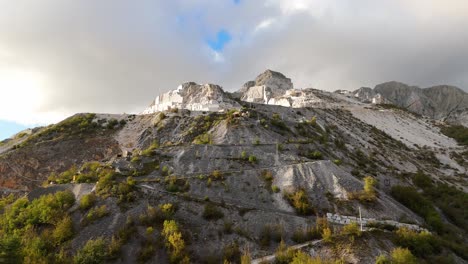 cantera de piedra caliza en los alpes de apua con árboles de otoño bajo cielos nublados, toscana, italia