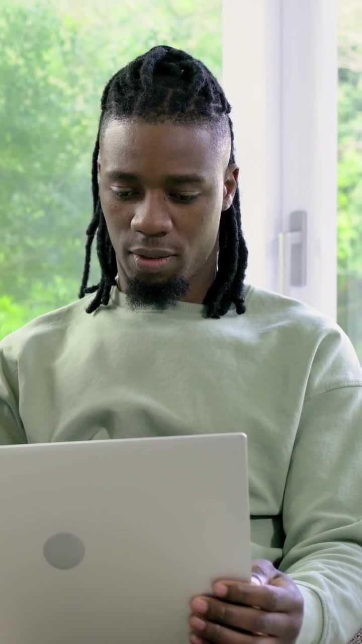 Vertical video: Entering woman in living room, opening laptop, man scrolling and smiling