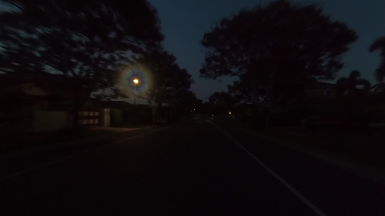 Punto di vista (POV) notturno posteriore alla guida per scena interna di auto con sostituzione schermo verde - una strada suburbana tranquilla e stretta con alberi e una curva a destra